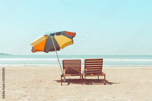 Fotografija Vintage toned two beach chairs and umberella on empty tropical ocean beach at su