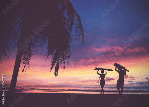 Obraz Sylwetka surfer ludzi niosących deski surfingowe na zachód słońca plaża