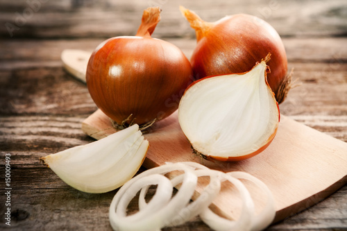 A sliced onion and fresh onions on cutting board
