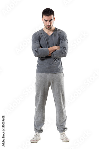 Tough young serious athletic sporty man staring at camera with crossed arms. Full body length portrait isolated on white studio background.  © sharplaninac