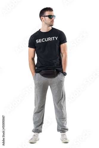 Tough young undercover police agent with waist bag and sunglasses looking away. Full body length portrait isolated on white studio background. 