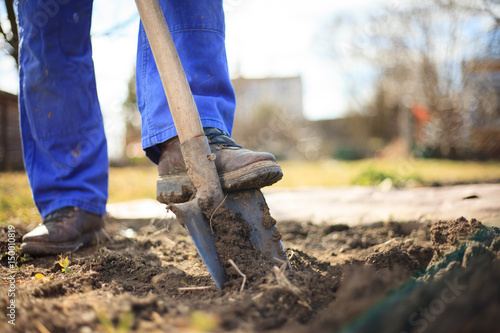 Senior man digging a garden for new plants after winter by spade