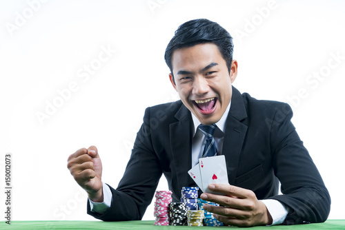 Fotografie The gambler is very happy to win poker cards and recieve bet a large stack