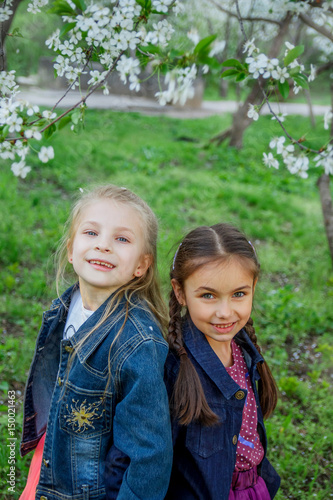 Two girls enjoying falling petals in spring garden