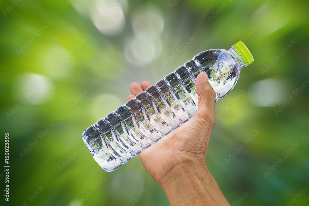 Man's hand holding drinking water bottle on blurred zoom bokeh zoom