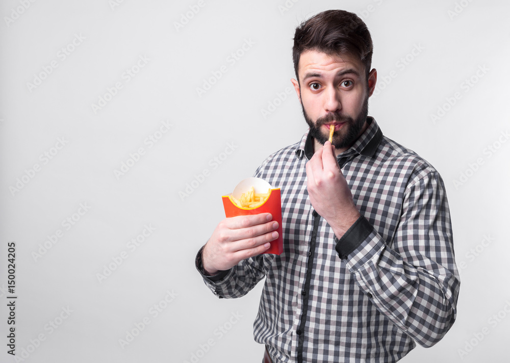 man holding a french fries . student eats fast food. not helpful food. very hungry guy man holding a french fries . student eats fast food. not helpful food. very hungry guy