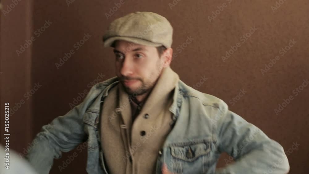 Young man putting on his denim jacket in front of the mirror Young man putting on his denim jacket in front of the mirror