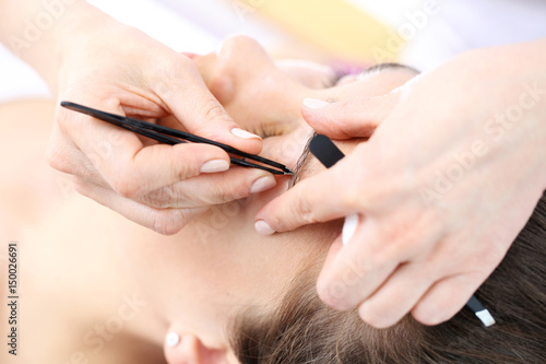 Henna i regulacja brwi. Kosmetyczka depiluje brwi klientki nadaj  c im odpowiedni kszta  t