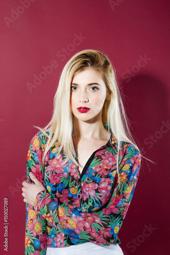 Sensual Blonde with Long Hair in Colorful Shirt is Looking at the Camera on Pink Background. Pretty Girl is Posing in Studio.