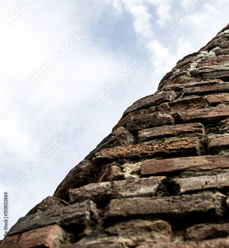 Old vintage brick wall on background a blue sky with clouds
