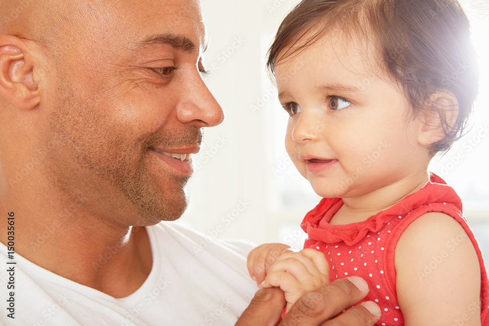 Mid adult man and baby daughter gazing at each other Mid adult man and baby daughter gazing at each other