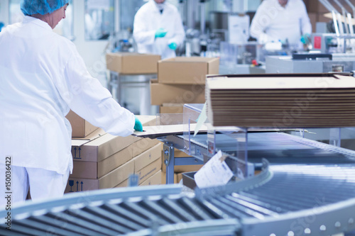 Workers packaging pharmaceutical products on production line in pharmaceutical plant photo