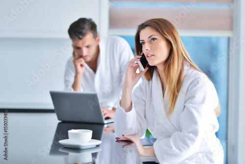 Picture a young woman eating breakfast and taking a phone call, sitting at the kitchen table.