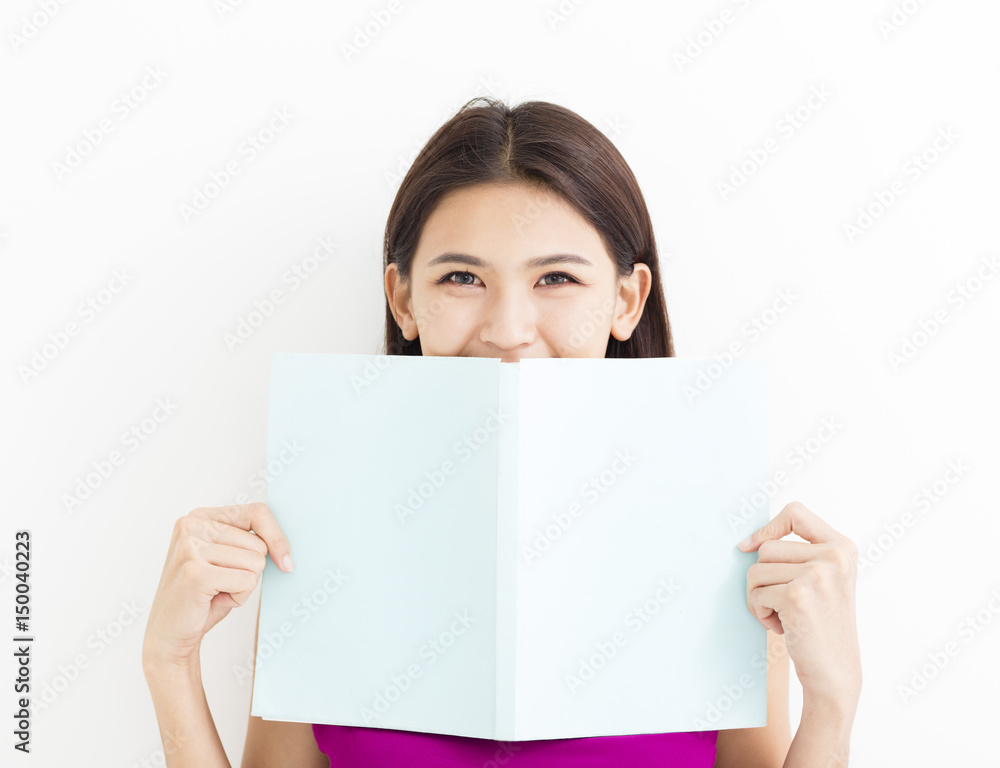 Smiling young woman reading book against white wall. Smiling young woman reading book against white wall.