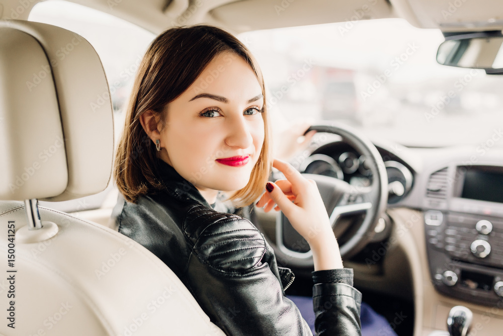 woman in car indoor keeps wheel turning around smiling looking at passengers in back seat idea taxi driver against sunset rays Light shine sky Concept of exam Vehicle - second home the girl woman in car indoor keeps wheel turning around smiling looking at passengers in back seat idea taxi driver against sunset rays Light shine sky Concept of exam Vehicle - second home the girl