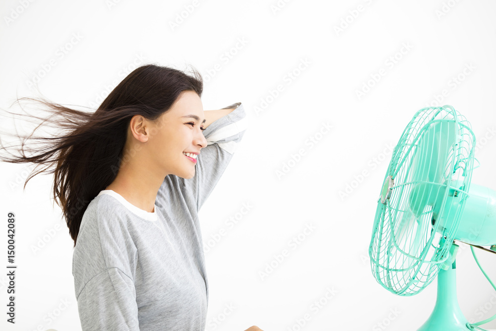 smiling woman cooling herself by electric fan smiling woman cooling herself by electric fan