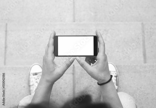 Woman holding modern smartphone. Horizontal mockup. Replaceable with own design. Landscape mode, 16:9 aspect ratio.Top view.