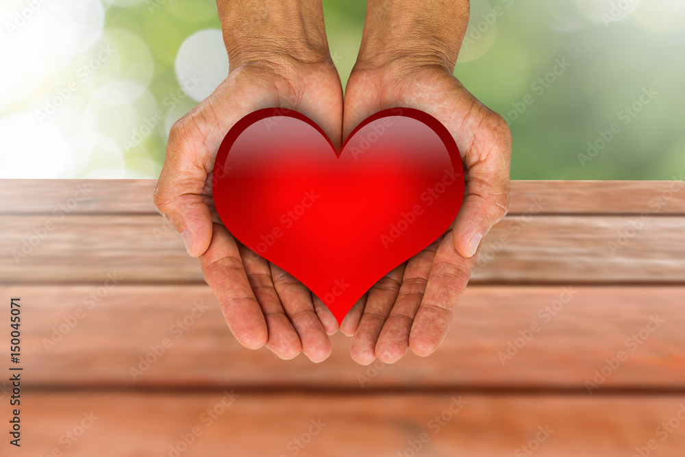 Man's hands holding red heart on blurred wooden and bokeh background Man's hands holding red heart on blurred wooden and bokeh background