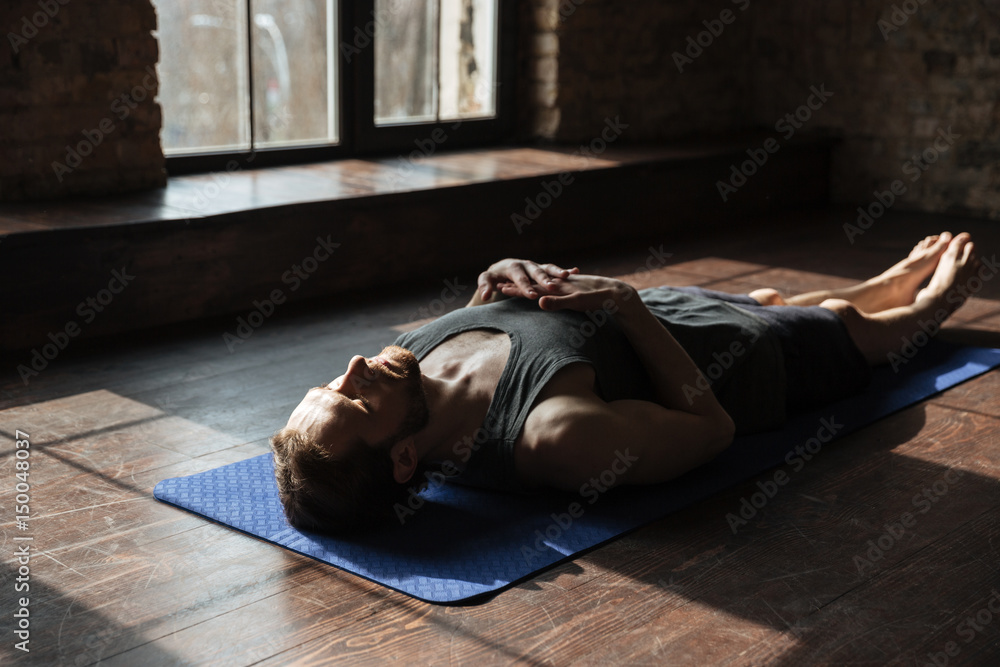 Handsome young strong sportsman in gym lies on floor Handsome young strong sportsman in gym lies on floor
