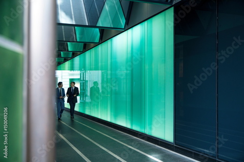 Businessmen walking through modern glass building, London, UK photo