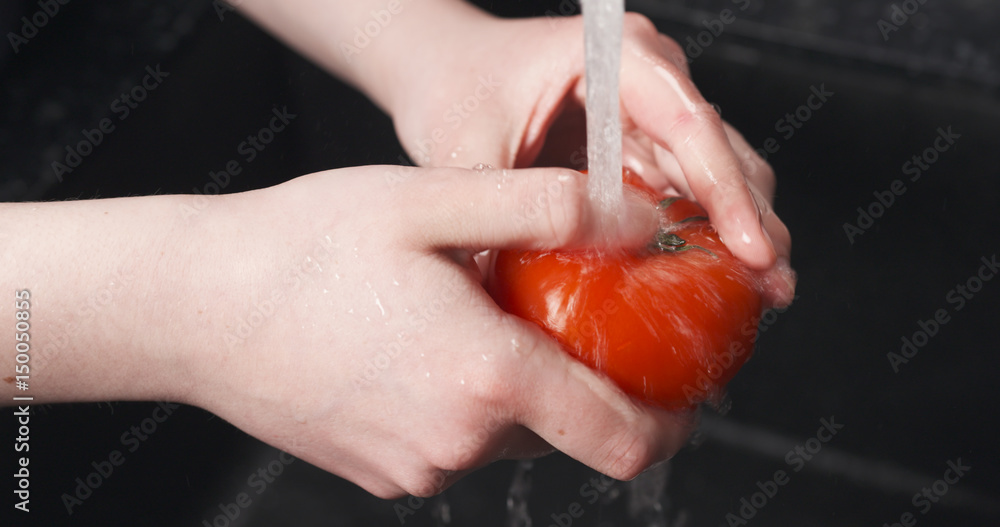 Handheld shot of female hands washing tomato, 4k photo Handheld shot of female hands washing tomato, 4k photo