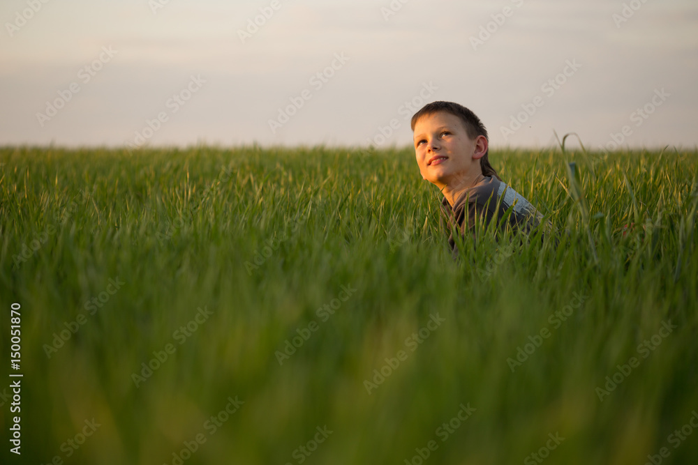 The teenager lies in the tall grass at sunset