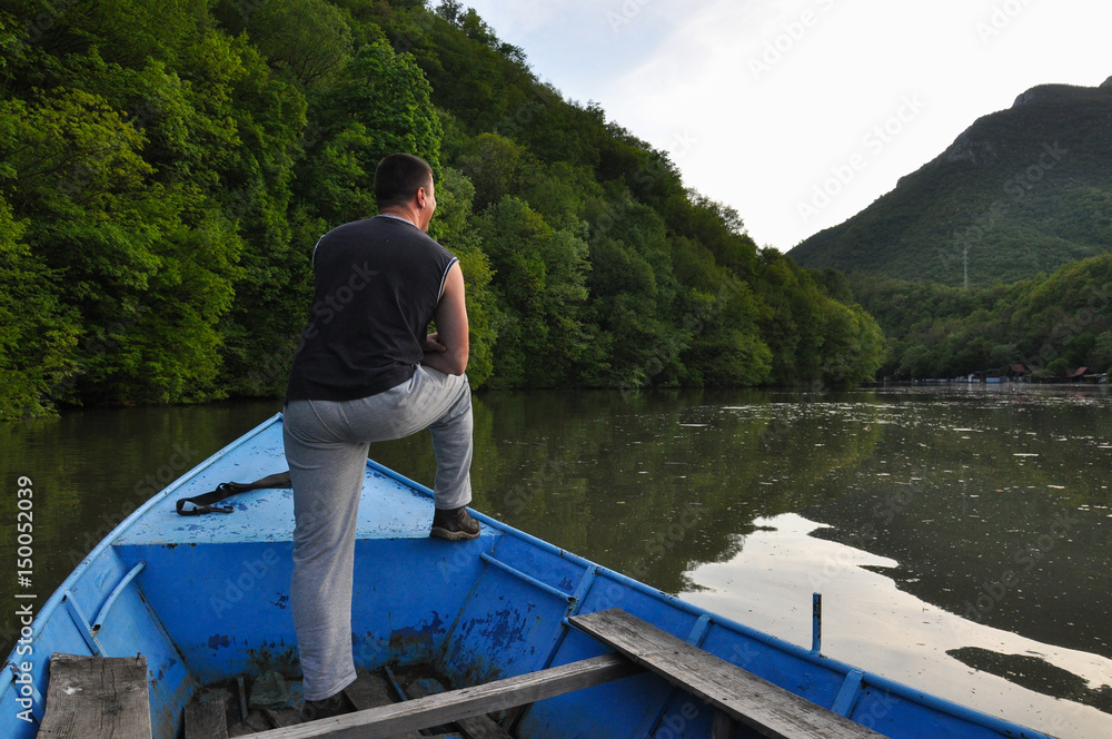 Man stands at the beginning of the small boat and looking forward Man stands at the beginning of the small boat and looking forward