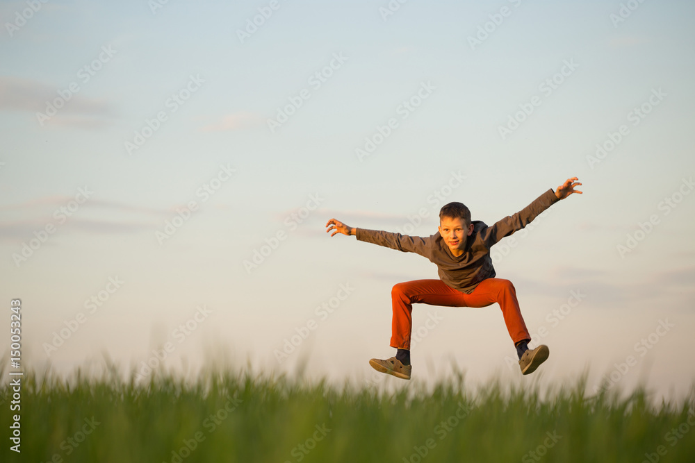 The teenager is flying over the field at sunset. The teenager is flying over the field at sunset.