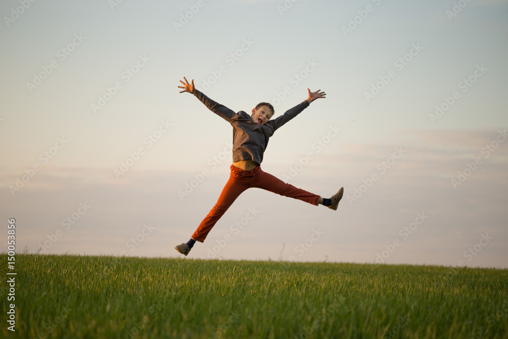 The teenager is flying over the field at sunset.