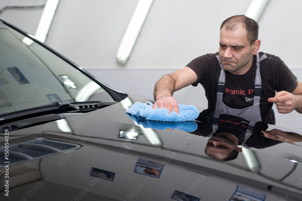 A man polishes a black car A man polishes a black car