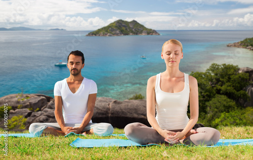 happy couple doing yoga and meditating outdoors
