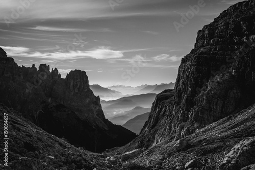 Black and white landscape view of hazy rolling mountains and hills in the Italian Dolomites at sunrise. Landscape orientation