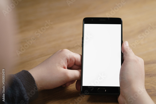 closeup shot of female teen hands with smartphone at the table, shallow focus