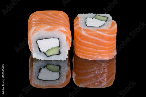 Rolls with cucumber, salmon and cream cheese on a black background with reflection