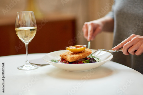 woman eating fish salad at cafe or restaurant