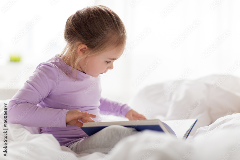 happy little girl reading book in bed at home happy little girl reading book in bed at home