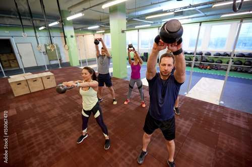 group of people with kettlebells exercising in gym © Syda Productions