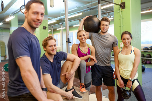 group of friends with sports equipment in gym