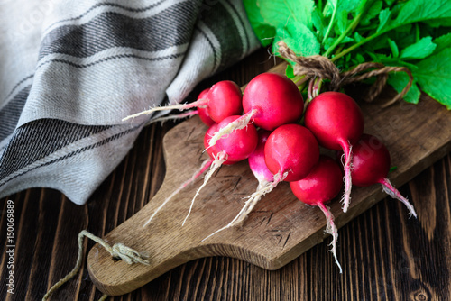 Bunch of fresh radish on wooden background and cutting board