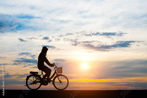 Silhouette, young women cycling with sunset.