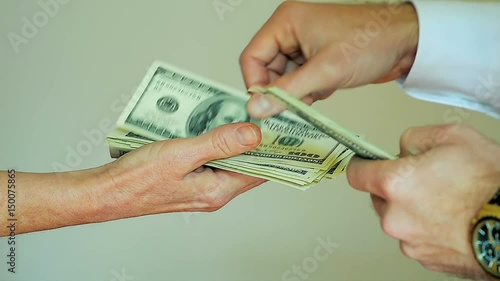Close-Up of Paying Cash from Man Hands Counting out 100 Dollar Bills into a Woman Hand