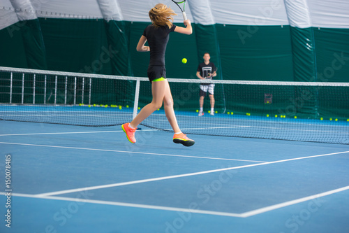 The young girl in a closed tennis court with ball