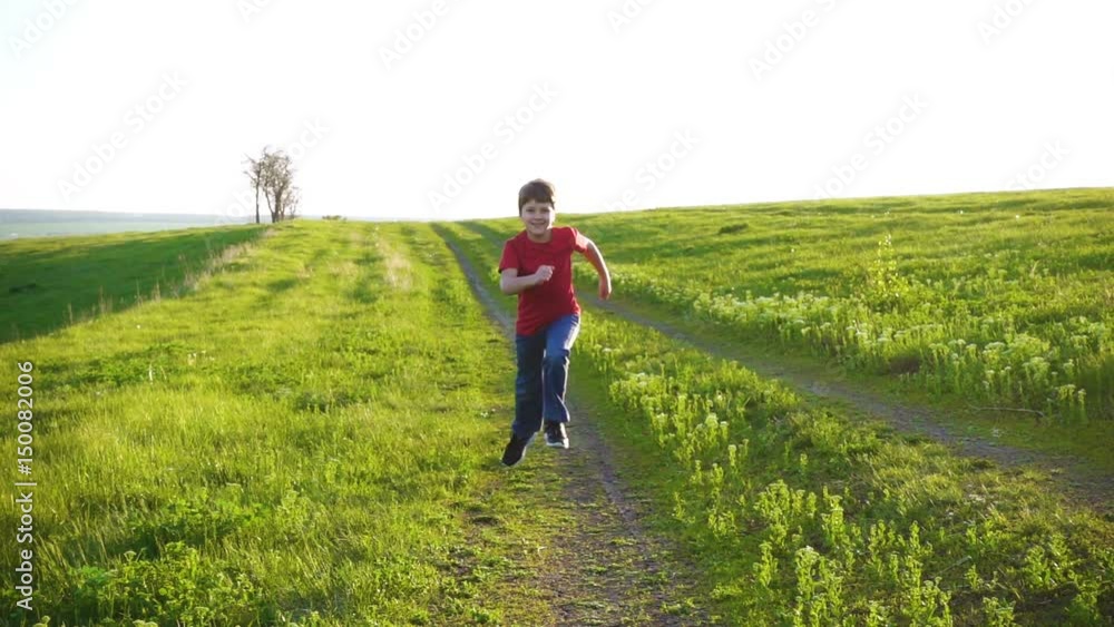 Happy boy running on rural road in green grass field Happy boy running on rural road in green grass field
