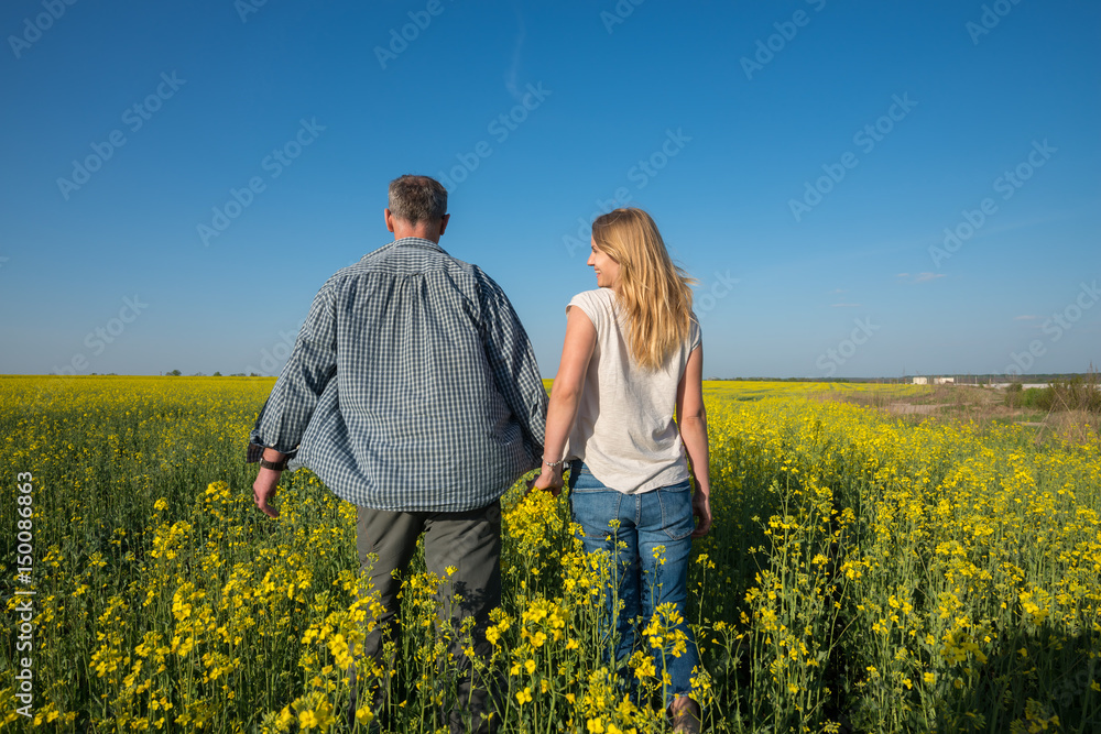 Man with a young smiling woman are walking through a field Man with a young smiling woman are walking through a field
