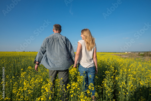 Man with a young smiling woman are walking through a field