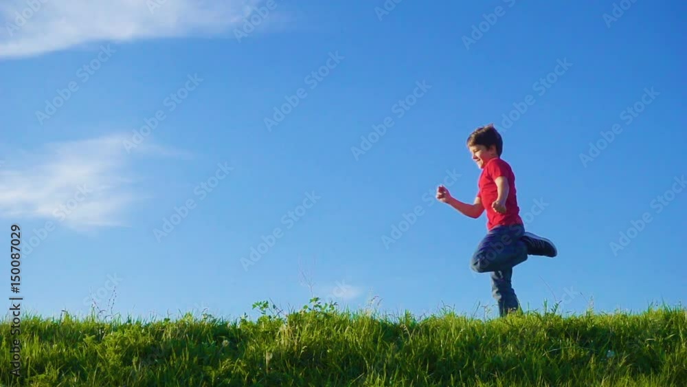 Happy boy running on green grass hill against blue sky Happy boy running on green grass hill against blue sky