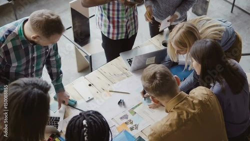 Top view of mixed race group of people standing near the table. Young business team working on start-up project together