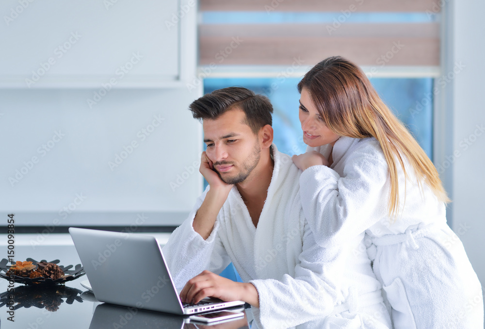 Portrait of a couple in the kitchen and using a laptop Portrait of a couple in the kitchen and using a laptop