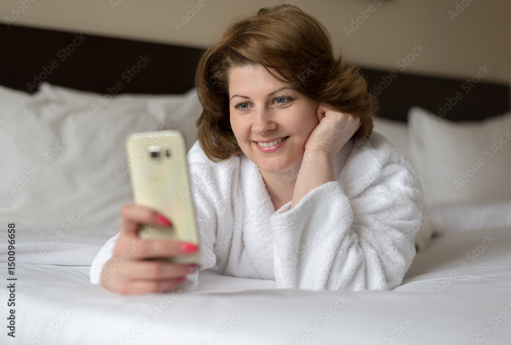A woman in bathrobe wears telephone in hotel room A woman in bathrobe wears telephone in hotel room