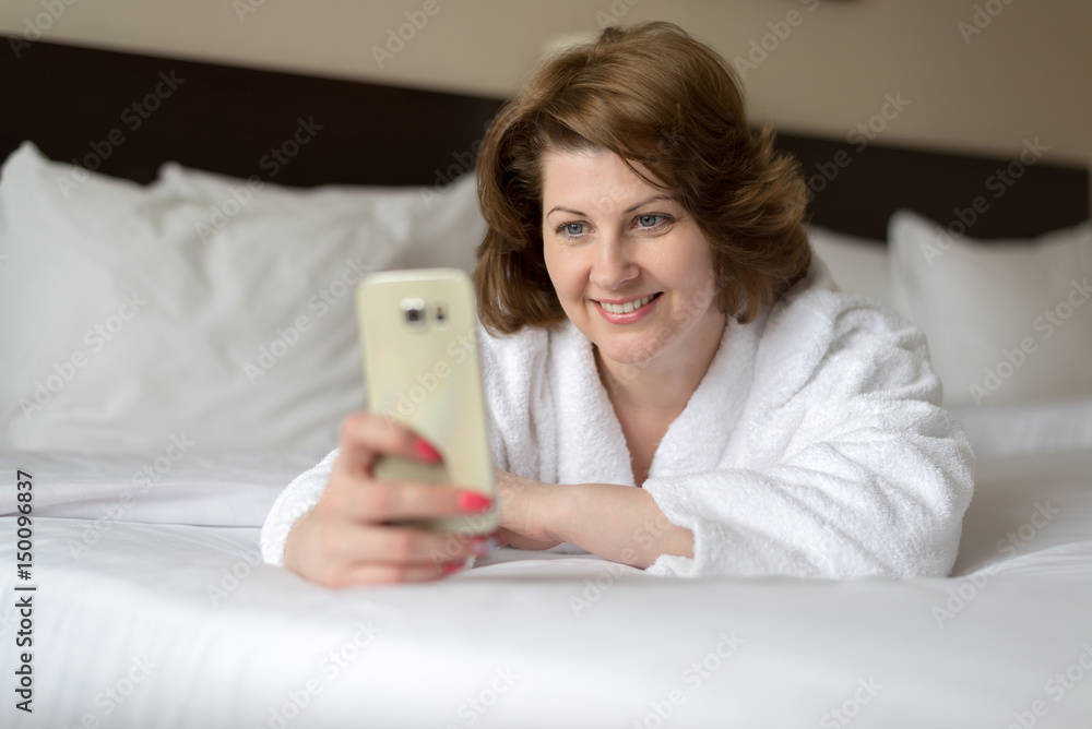 A woman in bathrobe wears telephone in hotel room A woman in bathrobe wears telephone in hotel room